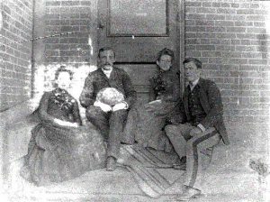 SWVMHI foto antigua con cuatro personas sentadas en los escalones junto al edificio