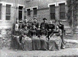 SWVMHI foto antigua con gente sentada cerca del edificio