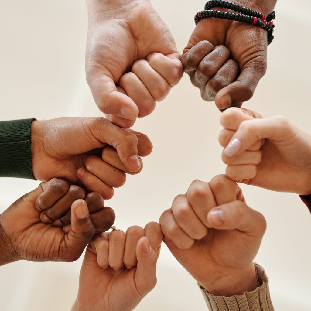 Siete manos con los puños que se tocan para formar un círculo que significa que se unen para apoyarse mutuamente. 