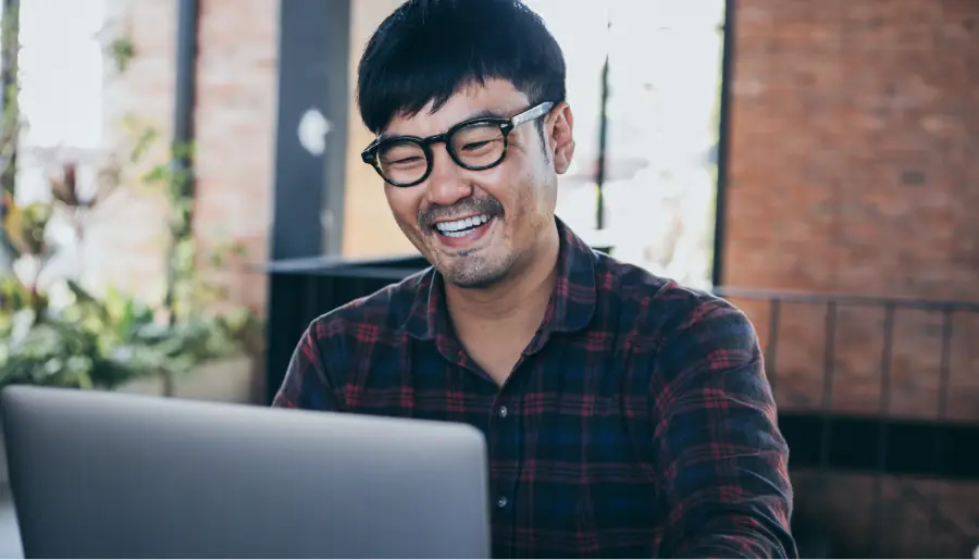 Hombre feliz trabajando usando la computadora y tipeando a mano el portátil
