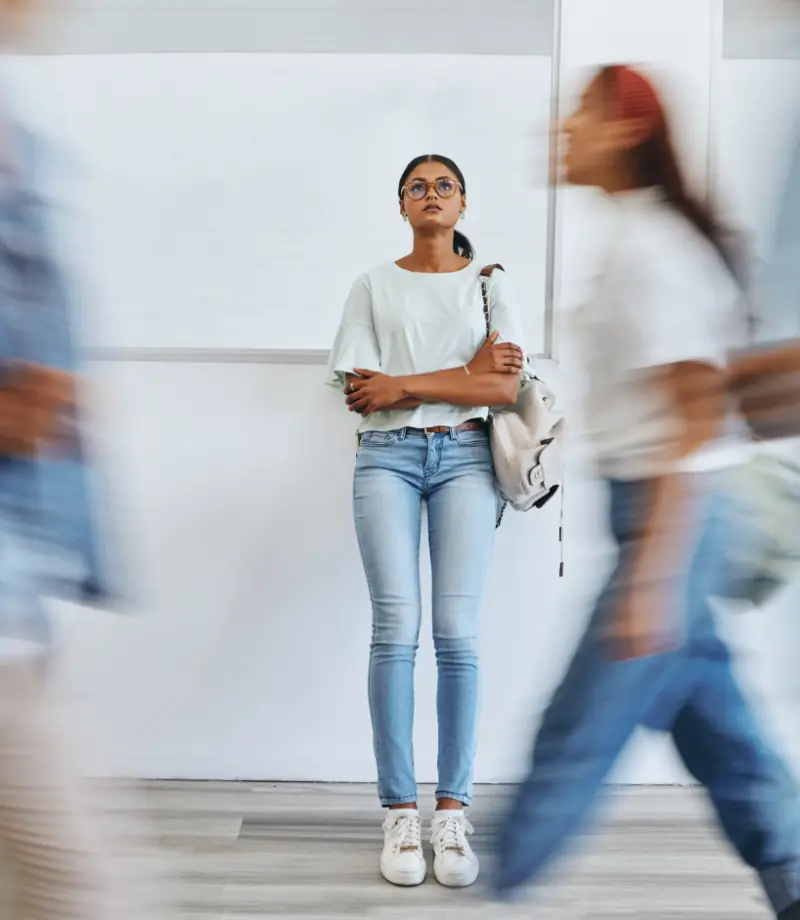 Estudiante, mujer con ansiedad y en un concurrido campus universitario con depresión, tristeza y problemas de salud mental.